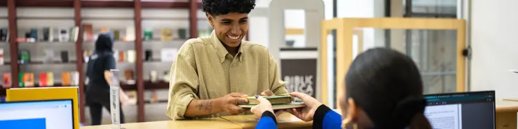 photo of a smiling man checking out a library book